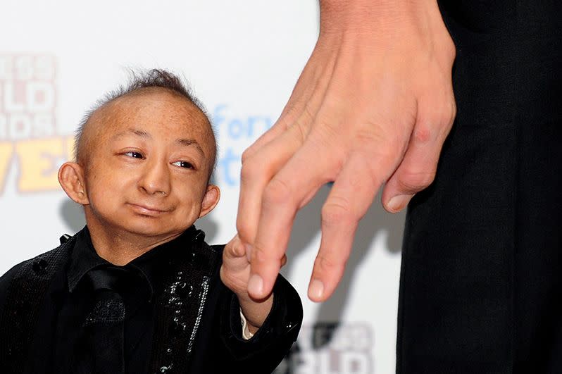 The world's smallest man, He Pingping, holds the hand of Guinness World Record holder Sultan Kosen. Photo: Getty.