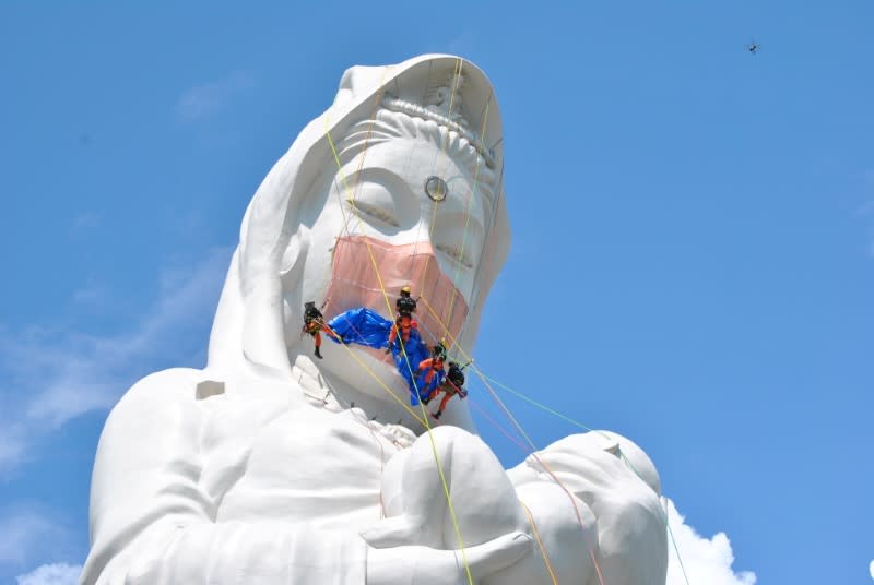 Workers place a mask on a 57-metre-high statue of Buddhist goddess Kannon to pray for the end of the coronavirus disease (COVID-19) pandemic at Houkokuji Aizu Betsuin temple in Aizuwakamatsu, Fukushima Prefecture, Japan