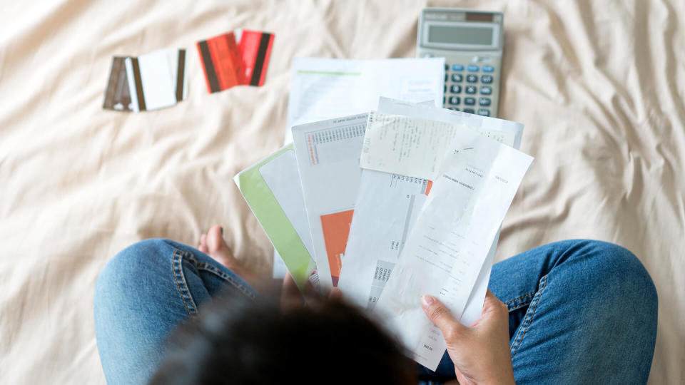 Top view of stressed young asian woman trying to find money to pay credit card debt.