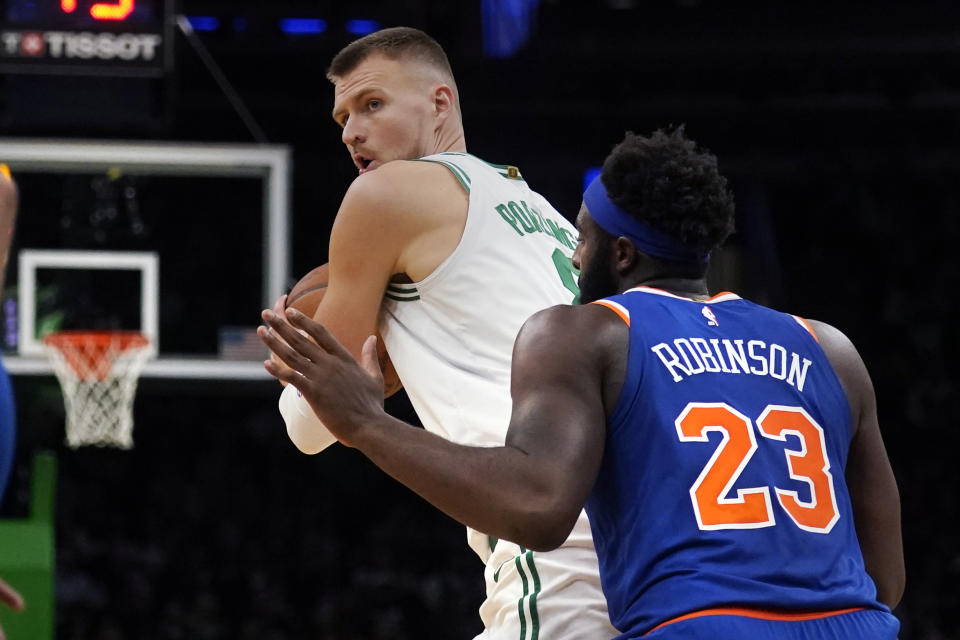 Boston Celtics center Kristaps Porzingis, left, looks to pass while covered by New York Knicks center Mitchell Robinson (23) during the second half of a preseason NBA basketball game, Tuesday, Oct. 17, 2023, in Boston. (AP Photo/Charles Krupa)