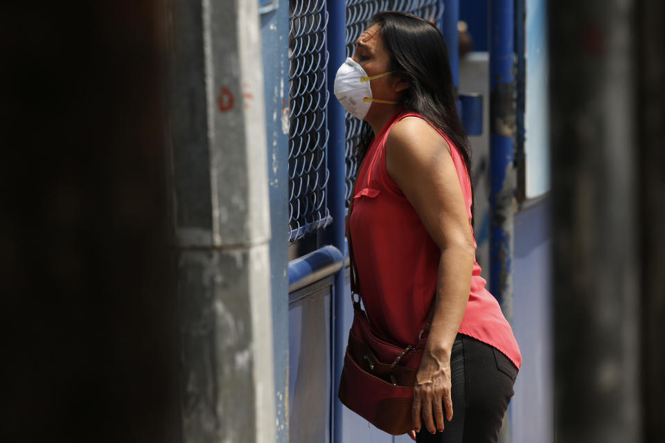 A woman waits for information, at the site where Guatemalans returned from the U.S. are being held in Guatemala City, Friday, April 17, 2020. Recently deported Guatemalans were placed in a athletic dorm facility to wait for the results of their tests for the new coronavirus. (AP Photo/Moises Castillo)