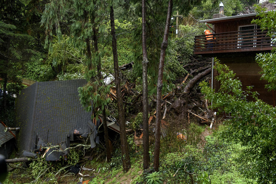 A worker looks out over a crushed house in the aftermath of a mudslide that destroyed three homes on a hillside in Sausalito, Calif., Thursday, Feb. 14, 2019. Waves of heavy rain pounded California on Thursday, filling normally dry creeks and rivers with muddy torrents, flooding roadways and forcing residents to flee their homes in communities scorched by wildfires. (AP Photo/Michael Short)