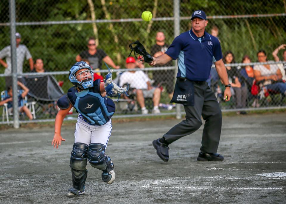 Firestorm catcher Zoey Hemphill attempts to catch a pop up of an attempted bunt while plate umpire Steve Caton follows the play.