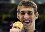 Michael Phelps of the U.S. celebrates with his gold medal at the men's 100m butterfly victory ceremony at the London 2012 Olympic Games at the Aquatics Centre August 3, 2012. REUTERS/Toby Melville (BRITAIN - Tags: SPORT OLYMPICS SPORT SWIMMING) 