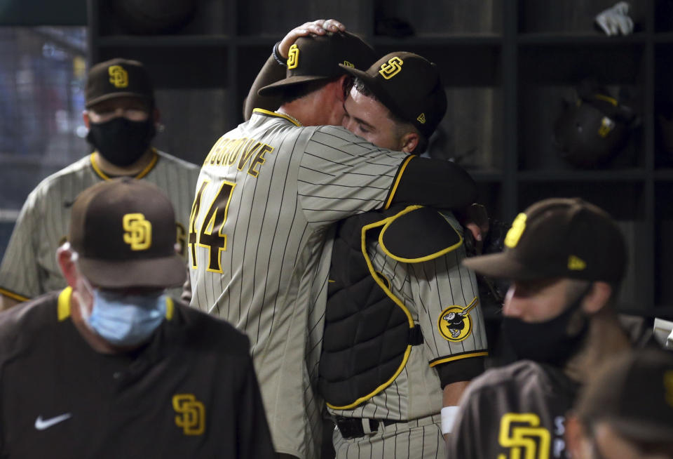 San Diego Padres starting pitcher Joe Musgrove (44) hugs catcher Victor Caratini (17) in the dugout after pitching a no-hitter against the Texas Rangers in a baseball game Friday, April 9, 2021, in Arlington, Texas. (AP Photo/Richard W. Rodriguez)