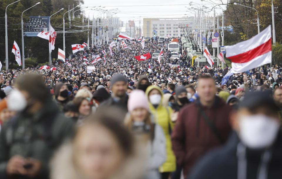 People with old Belarusian national flags march during an opposition rally to protest the official presidential election results in Minsk, Belarus, Sunday, Oct. 18, 2020. Hundreds of thousands of Belarusians have been protesting daily since the Aug. 9 presidential election. (AP Photo)