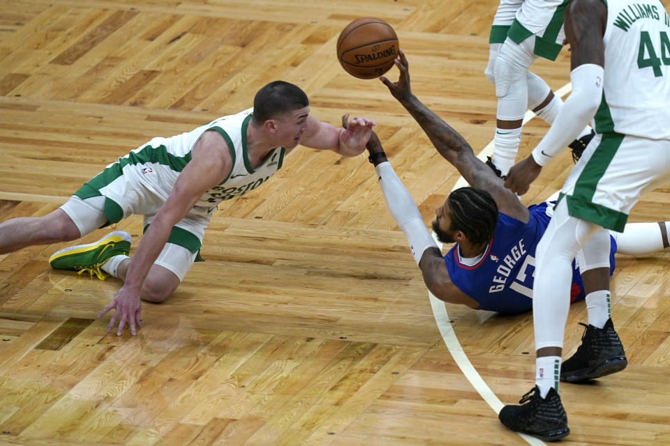 LA Clippers guard Paul George (13) passes the ball after a floor scramble against Boston Celtics guard Payton Pritchard, left, in the second quarter of an NBA basketball game, Tuesday, March 2, 2021, in Boston. (AP Photo/Elise Amendola)