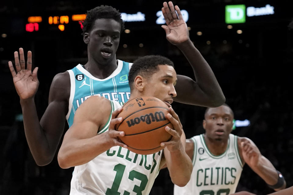 Boston Celtics' Malcolm Brogdon (13) drives toward the basket past Charlotte Hornets' JT Thor, back left, in the second half of a preseason NBA basketball game, Sunday, Oct. 2, 2022, in Boston. (AP Photo/Steven Senne)