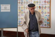 A man leaves a voting booth carrying his ballot paper at a polling station in Lisbon Sunday, Oct. 6, 2019. Portugal is holding a general election Sunday in which voters will choose members of the next Portuguese parliament. (AP Photo/Armando Franca)