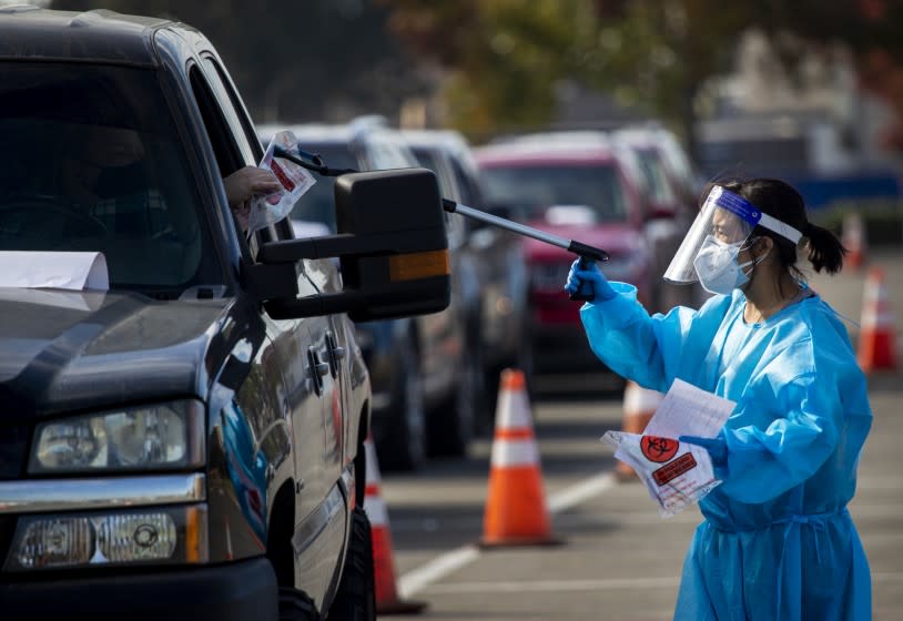 COSTA MESA, CA - NOVEMBER 12: A 360 Clinic health care worker working with the Orange County Health Care Agency and city of Costa Mesa conducts testing at the drive-through self-administered COVID-19 testing super site at the Orange County Fair & Events Center on Thursday, Nov. 12, 2020 in Costa Mesa, CA. California is approaching 1 million cases, although the spread remains slower in the state than in other hot spots across the country. (Allen J. Schaben / Los Angeles Times)