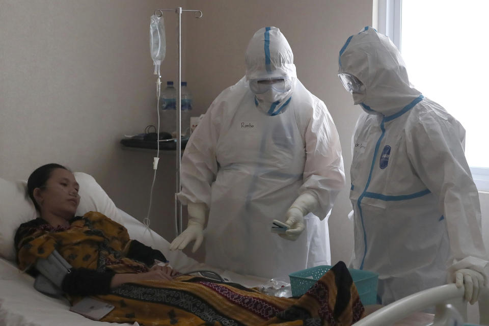 Dr. Irman Pahlepi, right, treats a COVID-19 patient at the Dr. Suyoto General Hospital in Jakarta, Indonesia, on July 29, 2021. Pahlepi is back at work in the hospital, immediately resuming his duties treating COVID-19 patients after recovering from an infection himself, for the second time. With numbers of infections in Indonesia skyrocketing and deaths steadily climbing, health care workers are being depleted as the virus spares nobody, Pahlepi felt he had no option but to jump right back in. (AP Photo/Tatan Syuflana)