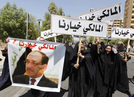 People hold a portrait of Nuri al-Maliki and signs as they gather in support of him in Baghdad August 13, 2014. REUTERS/Ahmed Saad