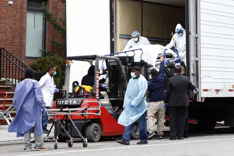 Workers load deceased person into truck trailer outside Brooklyn Hospital Center during the coronavirus disease (COVID-19) in New York