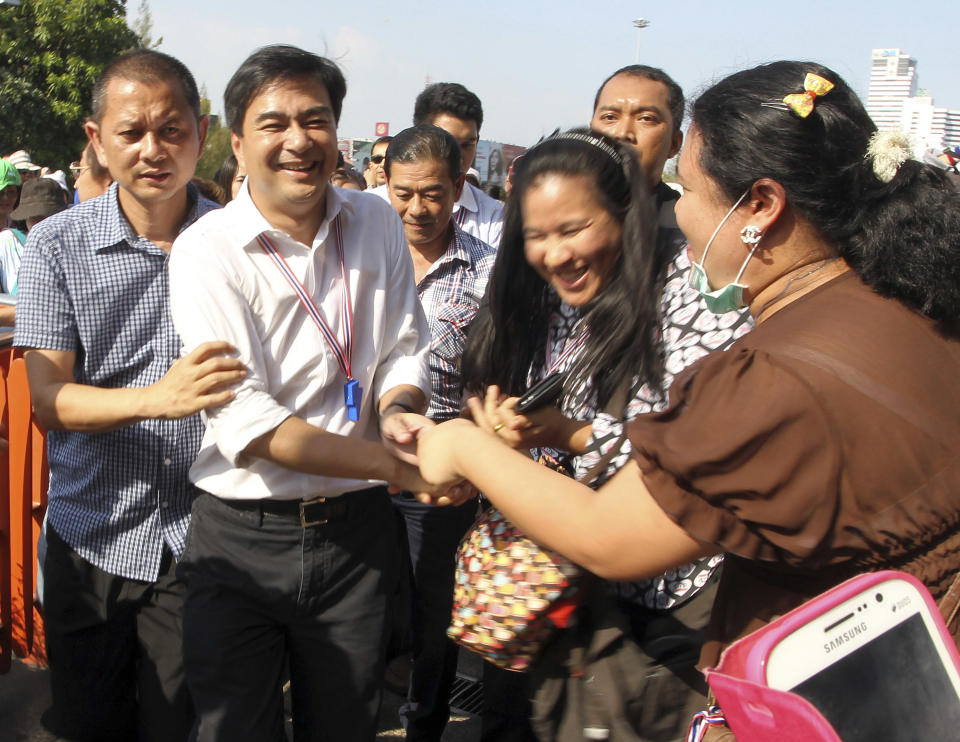 Former Thai Prime Minister Abhisit Vejjajiva, second left, is greeted by supporters as he appears at an overfly near the Victory Monument as thousands of protestors gather for a rally in Bangkok, Thailand Monday, Jan. 13, 2014. Anti-government protesters aiming to shut down central Bangkok took over key intersections Monday, halting much of the traffic into the Thai capital's main business district as part of a months-long campaign to overthrow the democratically elected prime minister. (AP Photo/Apichart Weerawong)