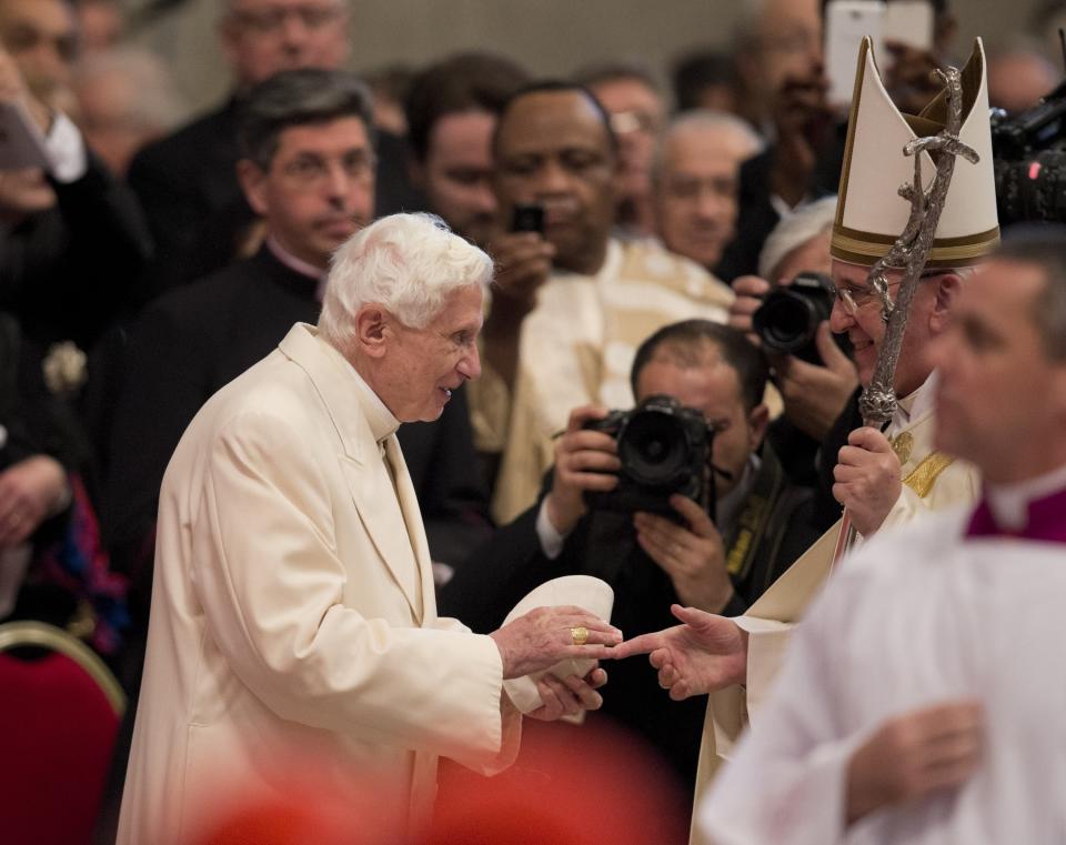 FILE - Pope Francis, right, salutes Pope Emeritus Benedict XVI, at the end of a consistory inside the St. Peter's Basilica at the Vatican, on Feb. 22, 2014. He was the reluctant pope, a shy bookworm who preferred solitary walks in the Alps and Mozart piano concertos to the public glare and majesty of Vatican pageantry. When Cardinal Joseph Ratzinger became Pope Benedict XVI and was thrust into the footsteps of his beloved and charismatic predecessor, he said he felt a guillotine had come down on him. The Vatican announced Saturday Dec. 31, 2022 that Benedict, the former Joseph Ratzinger, had died at age 95. (AP Photo/Alessandra Tarantino, File)