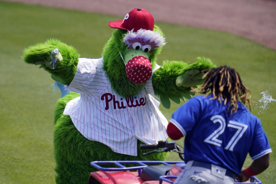 La mascota de los Filis de Filadelfia y Vladimir Guerrero Jr. de los Azulejos de Toronto durante un juego de pretemporada en Clearwater, Florida, el martes 16 de marzo de 2021. (AP Foto/Gene J. Puskar)