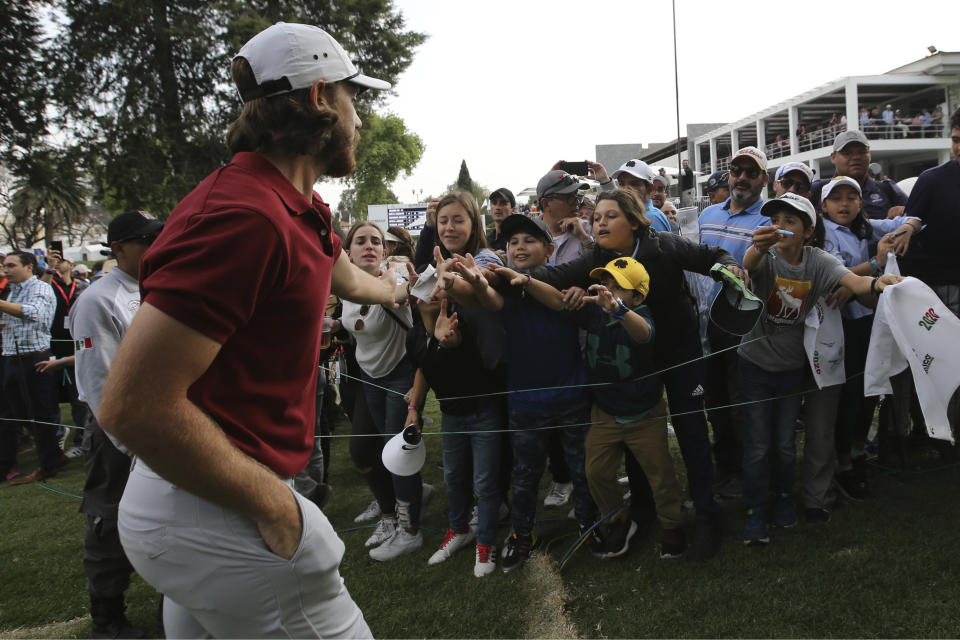 Tommy Fleetwood of England slaps the hands of fans as he leaves the 18th green at the end of the WGC-Mexico Championship golf tournament second round, at the Chapultepec Golf Club in Mexico City, Friday, Feb. 21, 2020. (AP Photo/Fernando Llano)