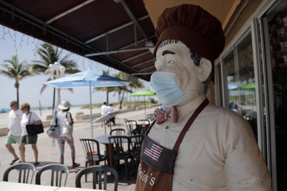 CORRECTS TO BROADWALK, INSTEAD OF BOARDWALK A statue of a chef at Florio's of Little Italy restaurant wears a protective face mask on the Hollywood Beach Broadwalk during the new coronavirus pandemic, Thursday, July 2, 2020, in Hollywood, Fla. In hard-hit South Florida, beaches from Palm Beach to Key West will be shut down for the Fourth of July holiday weekend. Restaurants and businesses along the Boardwalk will remain open. (AP Photo/Lynne Sladky)
