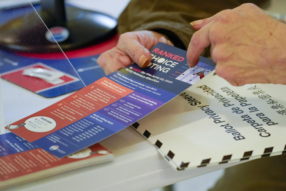 An election worker goes over a ranked choice voting explanation card with a voter before she casts her vote during early voting in the primary election, Monday, June 14, 2021, at the Church of St. Anthony of Padua in the Soho neighborhood of New York. (AP Photo/Mary Altaffer)