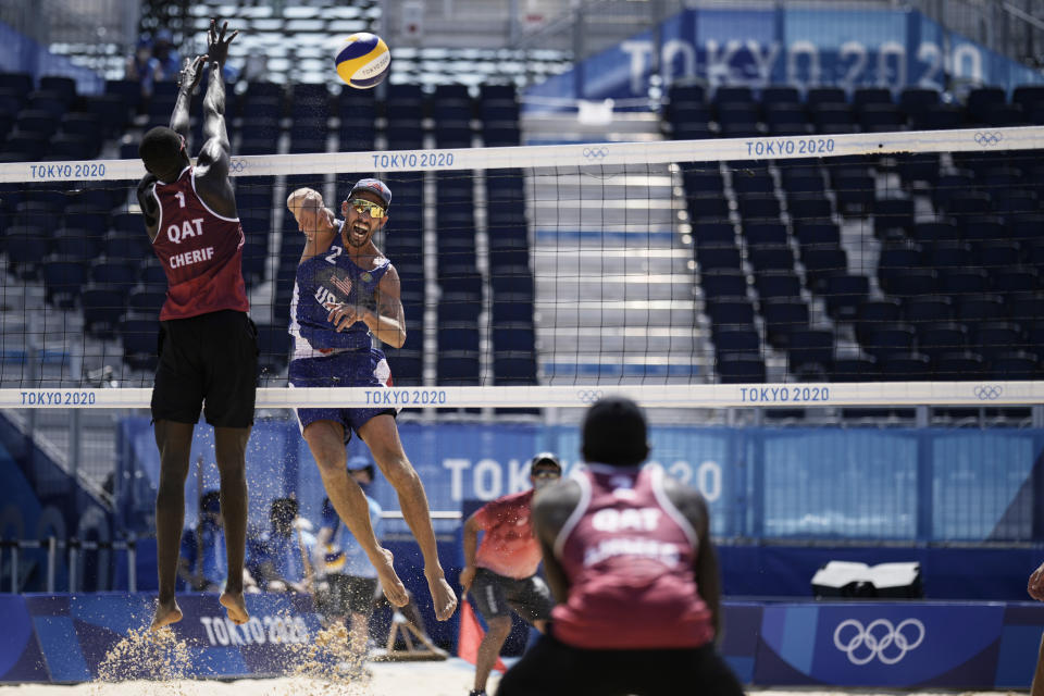 Nicholas Lucena, center, of the United States, takes a shot as Cherif Younousse, left, of Qatar, and teammate Ahmed Tijan defend during a men's beach volleyball match at the 2020 Summer Olympics, Sunday, Aug. 1, 2021, in Tokyo, Japan. (AP Photo/Felipe Dana)