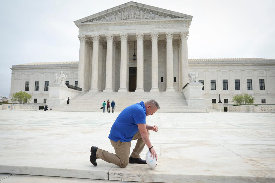 Former Bremerton High School assistant football coach Joe Kennedy takes a knee in front of the U.S. Supreme Court after his legal case, Kennedy vs. Bremerton School District, was argued before the court on April 25, 2022 in Washington, D.C. Kennedy was terminated from his job by Bremerton public school officials in 2015 after refusing to stop his on-field prayers after football games. Last month, a 6-3 majority said that coach's prayers were a form of private speech, protected by the First Amendment.