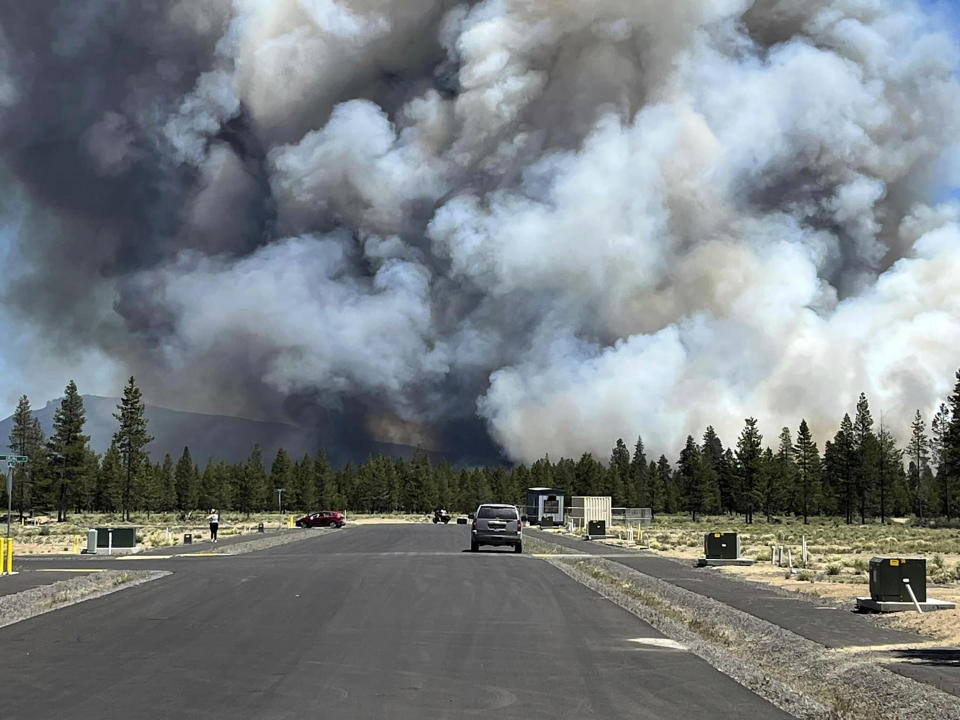 Smoke from a wildfire rises on a road near La Pine, Ore., Tuesday, June 25, 2024. The fire prompted mandatory evacuations in the small town in central Oregon and was growing rapidly in hot, dry conditions. (Jim Pharris via AP)