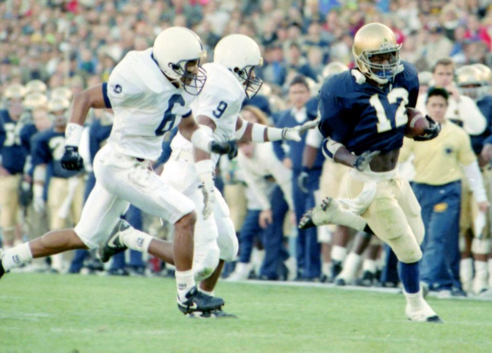 Notre Dame's Ricky Watters (12) breaks away from Penn State defenders Leonard Humphries (6) and Darren Perry (9)  a touchdown during his Irish playing days.nTribune file photo/PAUL RAKESTRAW