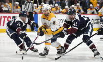 Nashville Predators center Thomas Novak, center, loses control of the puck while driving between Colorado Avalanche defenseman Samuel Girard, left, and left wing Darren Helm in the second period of an NHL hockey game Saturday, Nov. 27, 2021, in Denver. (AP Photo/David Zalubowski)