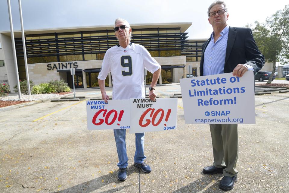 FILE - Members of SNAP, the Survivors Network of those Abused by Priests, including Richard Windmann, left, and John Gianoli, right, hold signs during a conference in front of the New Orleans Saints training facility in Metairie, La., Wednesday Jan. 29, 2020. U.S. District Judge Greg Guidry donated tens of thousands of dollars to New Orleans’ Roman Catholic archdiocese and consistently ruled in favor of the church amid a contentious bankruptcy involving nearly 500 clergy sex abuse victims, The Associated Press found, an apparent conflict that could throw the case into disarray. (AP Photo/Matthew Hinton, File)