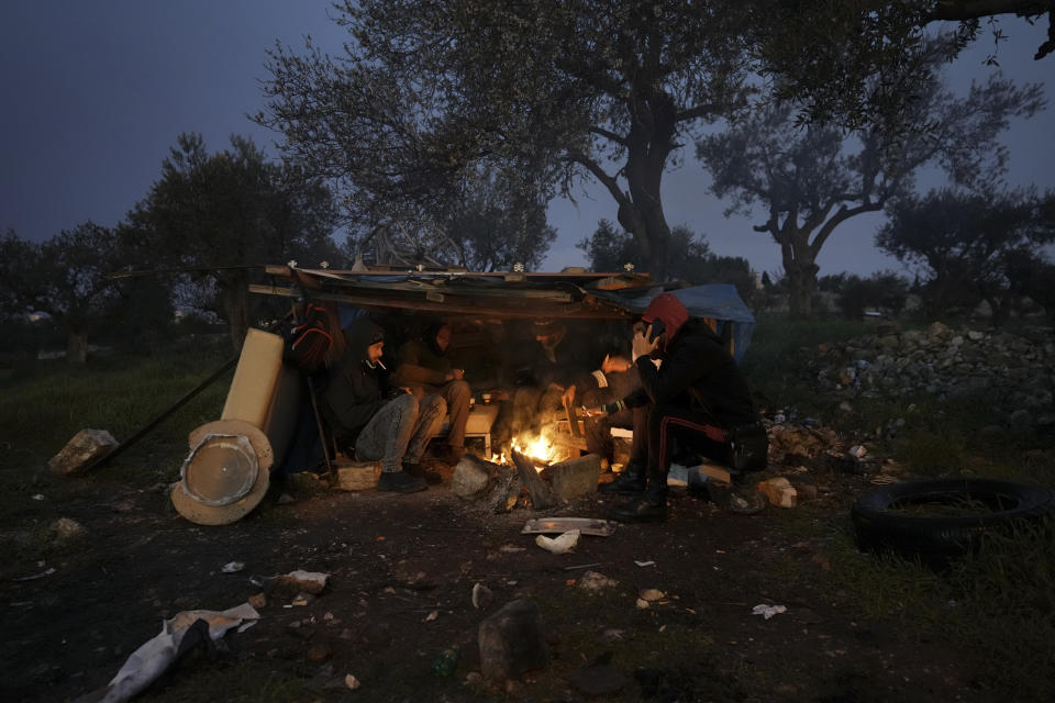 FILE - Palestinian laborers warm themselves around a fire as they wait for transportation after crossing a checkpoint from the West Bank city of Bethlehem into Jerusalem, Tuesday, March 15, 2022. The apparent comeback of former Prime Minister Benjamin Netanyahu and the dramatic rise of his far-right and ultra-Orthodox allies in Israel's general election this week have prompted little more than shrugs from many Palestinians. (AP Photo/Mahmoud Illean, File)