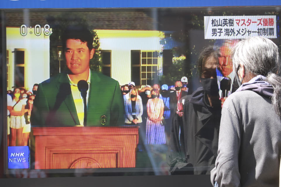 A passerby watches a tv news report showing Japanese golfer Hideki Matsuyama in the Masters, in Tokyo, Monday, April 12, 2021. From Japan's prime minister on down, the country celebrated Matsuyama's victory in the Masters — the first Japanese to win at Augusta National and wear the famous green jacket.(AP Photo/Koji Sasahara)