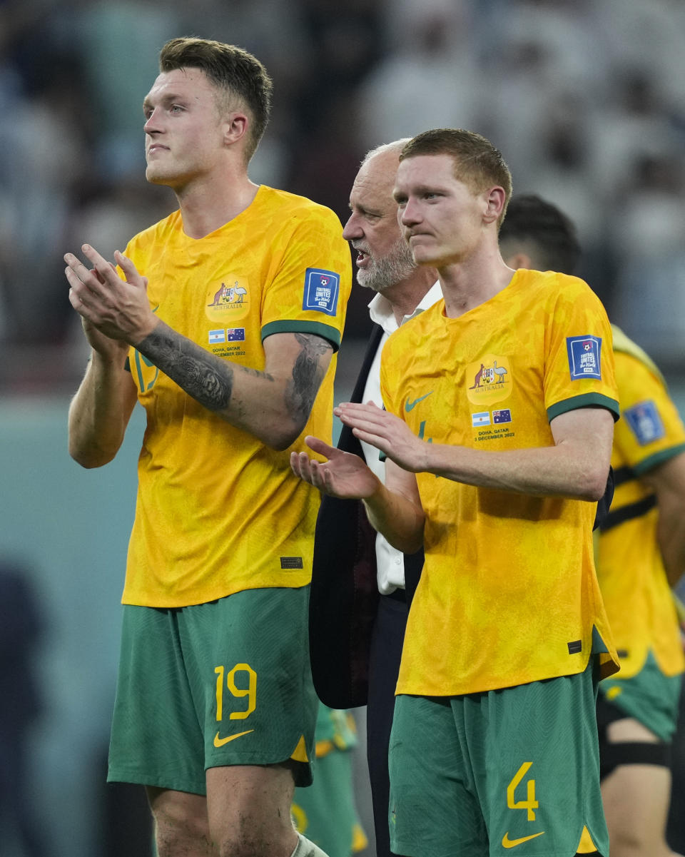 Australia's Harry Souttar, left, head coach Graham Arnold and Kye Rowles react to supporters following the World Cup round of 16 soccer match between Argentina and Australia at the Ahmad Bin Ali Stadium in Doha, Qatar, Saturday, Dec. 3, 2022. (AP Photo/Jorge Saenz)