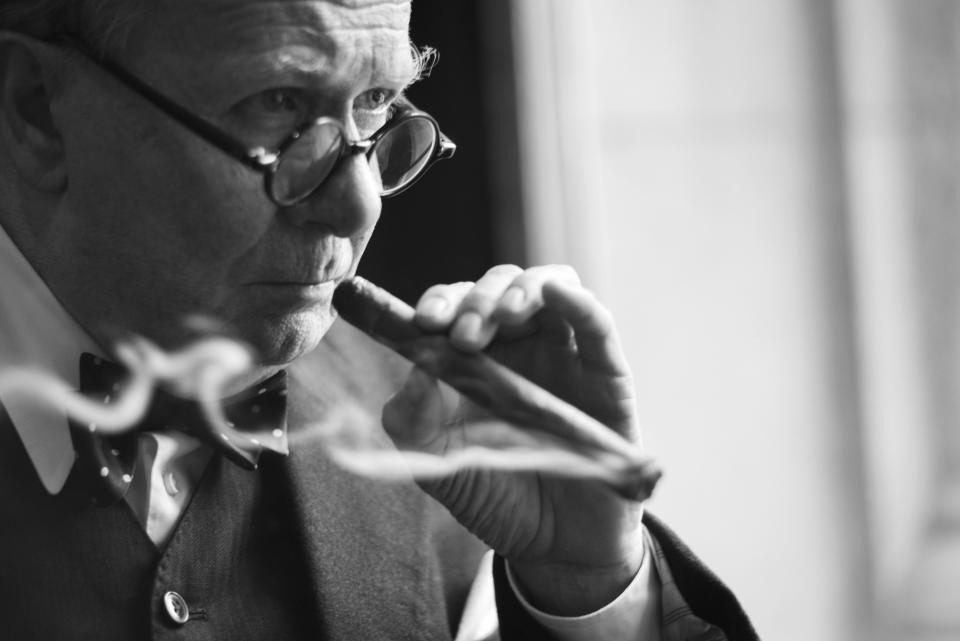 A close up of Oldman smoking a cigar