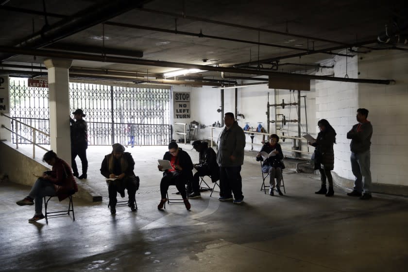 FILE - In this March 13, 2020, file photo, unionized hospitality workers wait in line in a basement garage to apply for unemployment benefits at the Hospitality Training Academy in Los Angeles. At least 350,000 debit cards filled with money for unemployment benefits in California have been frozen because of suspected fraud. (AP Photo/Marcio Jose Sanchez, File)