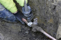 New copper tubing, left, is attached to the water main at a home in Royal Oak, Mich., on Tuesday, Nov. 16, 2021. Communities with lead pipes could see higher test results for lead in their tap water if a new method of water sampling goes into effect. The Detroit suburb of Royal Oak historically had low test results but it had to notify the public of a problem after the state mandated new sampling methods. (AP Photo/Carlos Osorio)