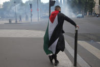 A demonstrator covered with a Palestinian flag stops at a street pole during a banned protest in support of Palestinians in the Gaza Strip, Saturday, May, 15, 2021 in Paris. Marches in support of Palestinians in the Gaza Strip were being held Saturday in a dozen French cities, but the focus was on Paris, where riot police got ready as organizers said they would defy a ban on the protest. (AP Photo/Michel Euler)