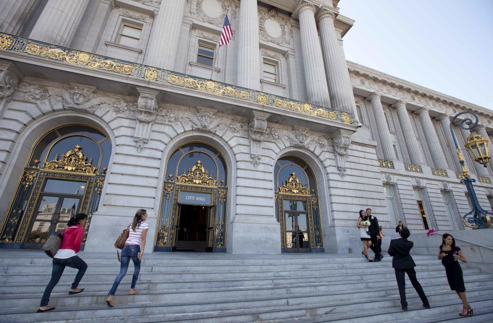 In this photo taken Thursday, Sept. 27, 2012, people pose for pictures and make their way up the steps to City Hall in San Francisco. San Francisco has a long history as a favorite site for filmmakers and the movie buffs who want to see the spots where their favorite scenes took place, from Fort Point under the Golden Gate Bridge where Jimmy Stewart saved Kim Novak in "Vertigo" to the steps of City Hall, where Sean Penn gave an impassioned speech in "Milk," to Alcatraz, stage for Clint Eastwood and many others. (AP Photo/Eric Risberg)