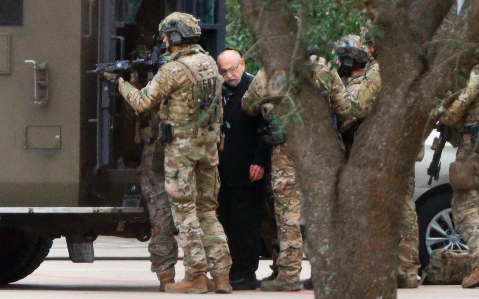 Authorities escort a hostage out of the Congregation Beth Israel synagogue in Colleyville, Texas, Saturday, Jan. 15, - The Dallas Morning News