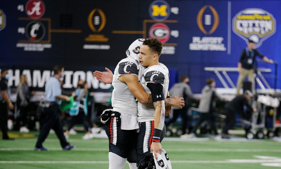 Cincinnati Bearcats wide receiver Blue Smith (83), left, and Bearcats quarterback Desmond Ridder hug after losing to University of Alabama 27-6 in the College Football Playoff Semifinal at the 86th  Cotton Bowl Classic Friday, December 31, 2021, at AT & T Stadium in Arlington, Texas.