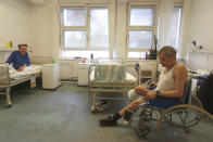 Patients sit in a ward of the hospital for the homeless in Budapest, Hungary, Thursday, April 14, 2021. A bitter conflict has emerged between Hungary’s right-wing government and the liberal leadership of the country's capital city over a hospital for the homeless that may soon have to close. The Budapest hospital provides medical and social services and shelter to more than 1,000 people annually. But the Hungarian government has ordered it to vacate the state-owned building it occupies. Budapest's mayor says the eviction will risk the lives of the hospital's homeless patients as Hungary struggles with a deadly COVID-19 surge. (AP Photo/Laszlo Balogh)