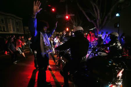 A man raises his hands while attempting to block the movement of a group of motorcycle police during a demonstration against the grand jury decision in the Ferguson, Missouri shooting of Michael Brown in San Francisco, California November 28, 2014. REUTERS/Stephen Lam