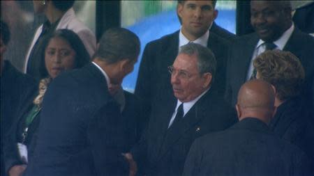 U.S. President Barack Obama (2nd L) shakes hands with Cuban President Raul Castro (C) in this still image taken from video courtesy of the South Africa Broadcasting Corporation (SABC) at the First National Bank (FNB) Stadium, also known as Soccer City, during former South African President Nelson Mandela's national memorial service in Johannesburg December 10, 2013. Obama shook the hand of Castro at a memorial to Mandela on Tuesday, an unprecedented gesture between the leaders of two nations which have been at loggerheads for more than half a century. REUTERS/SABC via Reuters TV