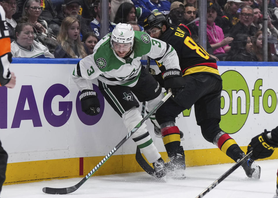 Dallas Stars' Chris Tanev (3) is checked by Vancouver Canucks' Arshdeep Bains (80) during the third period of an NHL hockey game Thursday, March 28, 2024, in Vancouver, British Columbia. (Darryl Dyck/The Canadian Press via AP)