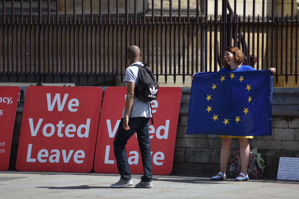 LONDON, ENGLAND - JULY 24: A girl holding an EU flag laughs with a pedestrian as he walks past "We voted Leave" boards outside the Houses of Parliament in Westminster on the day Boris Johnson becomes the new Prime Minister on July 24, 2019 in London, England. (Photo by John Keeble/Getty Images)