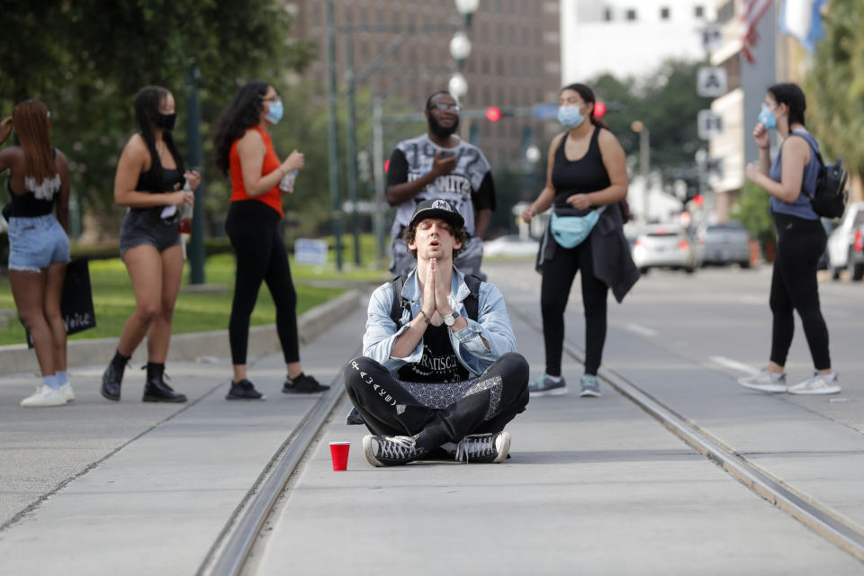 Un manifestante, que se identificó sólo como "J", gesticula sentado mientras otros manifestantes bloquean brevemente la avenida Loyola en el centro de Nueva Orleans, el martes 2 de junio de 2020, durante una protesta por la muerte de George Floyd, después de ser sometido por la policía de Mineápolis. (AP Foto/Gerald Herbert)