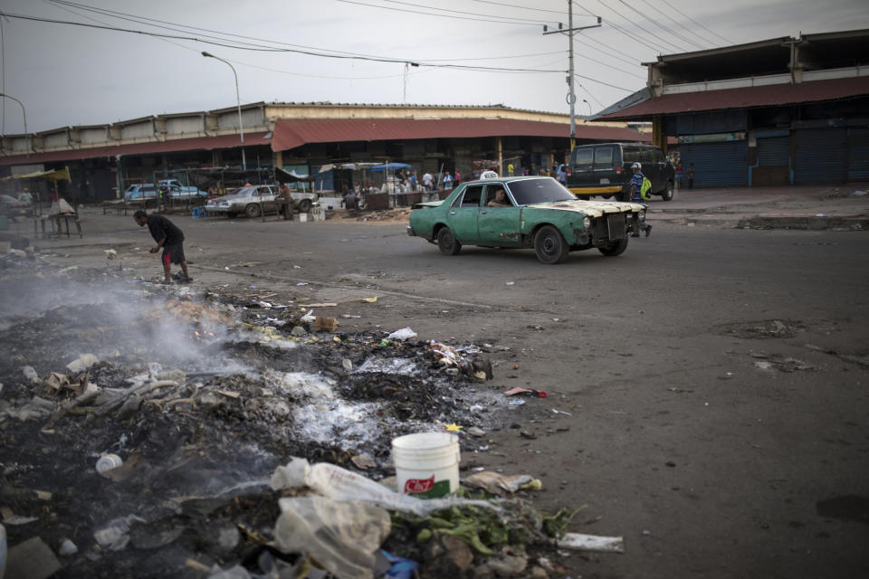 A man searches the trash outside a flea market in Maracaibo, Venezuela, May 14, 2019. As the political standoff drags on, so does life in Maracaibo, where some people sift through trash and scavenge for food. (AP Photo/Rodrigo Abd)