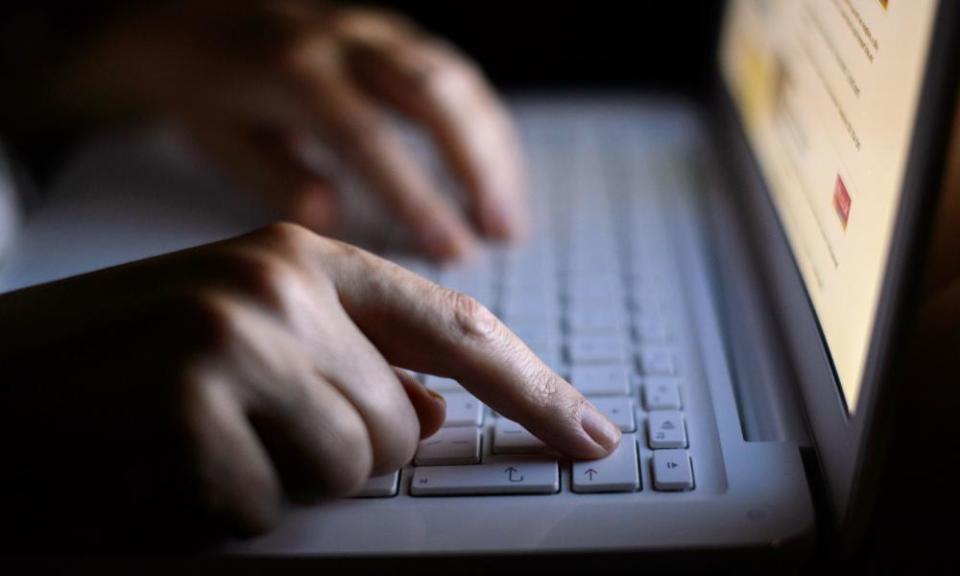 A person using a laptop, room fairly dark