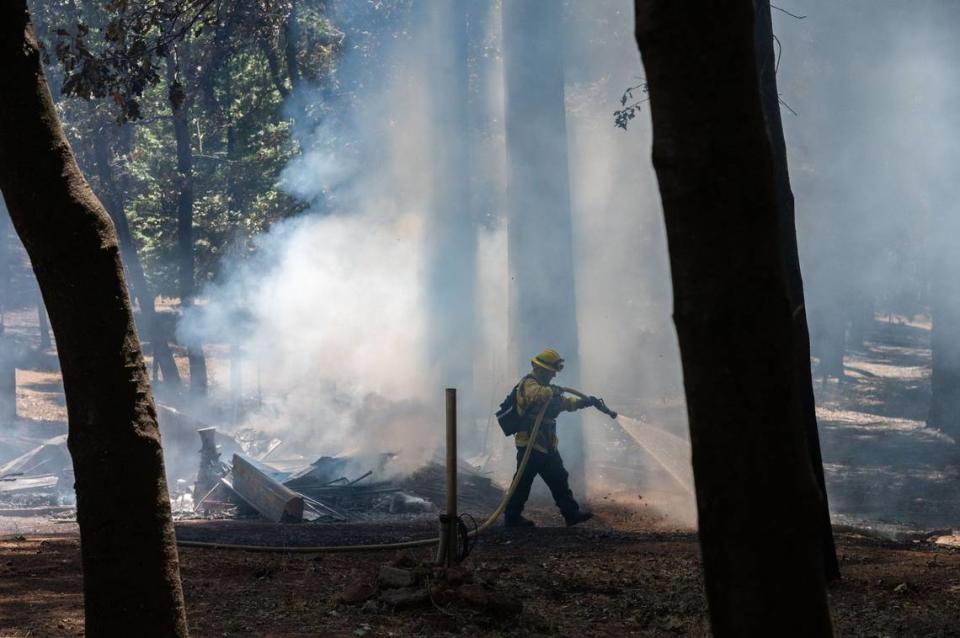 A firefighter with the Monterey Fire Department hoses down smoldering rubble in Cohasset on July 26. A group of firefighters put out hot spots to prevent fires from further damaging remaining structures in the area.