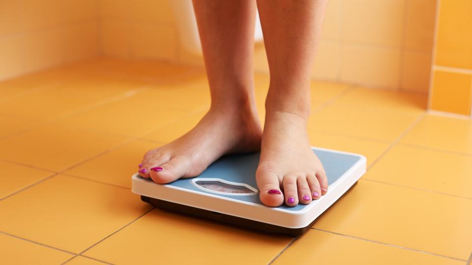A pair of female feet standing on a bathroom scale.