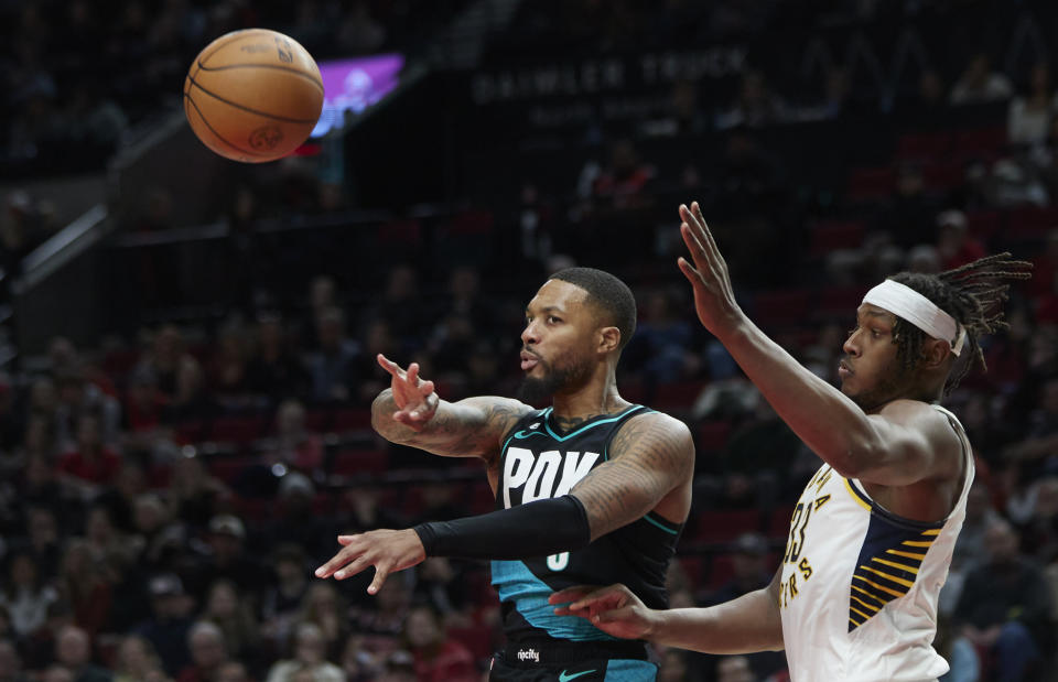 Portland Trail Blazers guard Damian Lillard, left, passes the ball away from Indiana Pacers center Myles Turner during the second half of an NBA basketball game in Portland, Ore., Sunday, Dec. 4, 2022. (AP Photo/Craig Mitchelldyer)